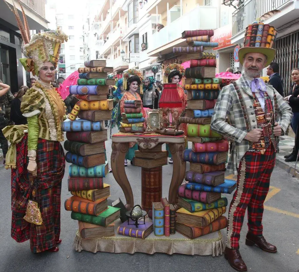 Disfraces de época junto a pilas de libros gigantes en el desfile del Carnaval de Nerja