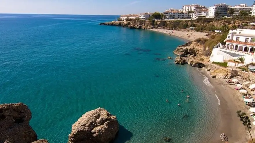Agua cristalina frente a la playa La Caletilla, con la costa de Nerja y sus apartamentos