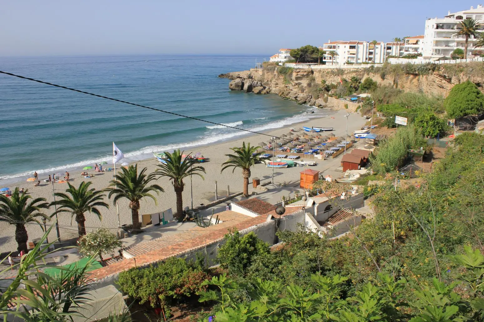 Palmeras y hamacas en la playa El Salón, vista desde la bajada