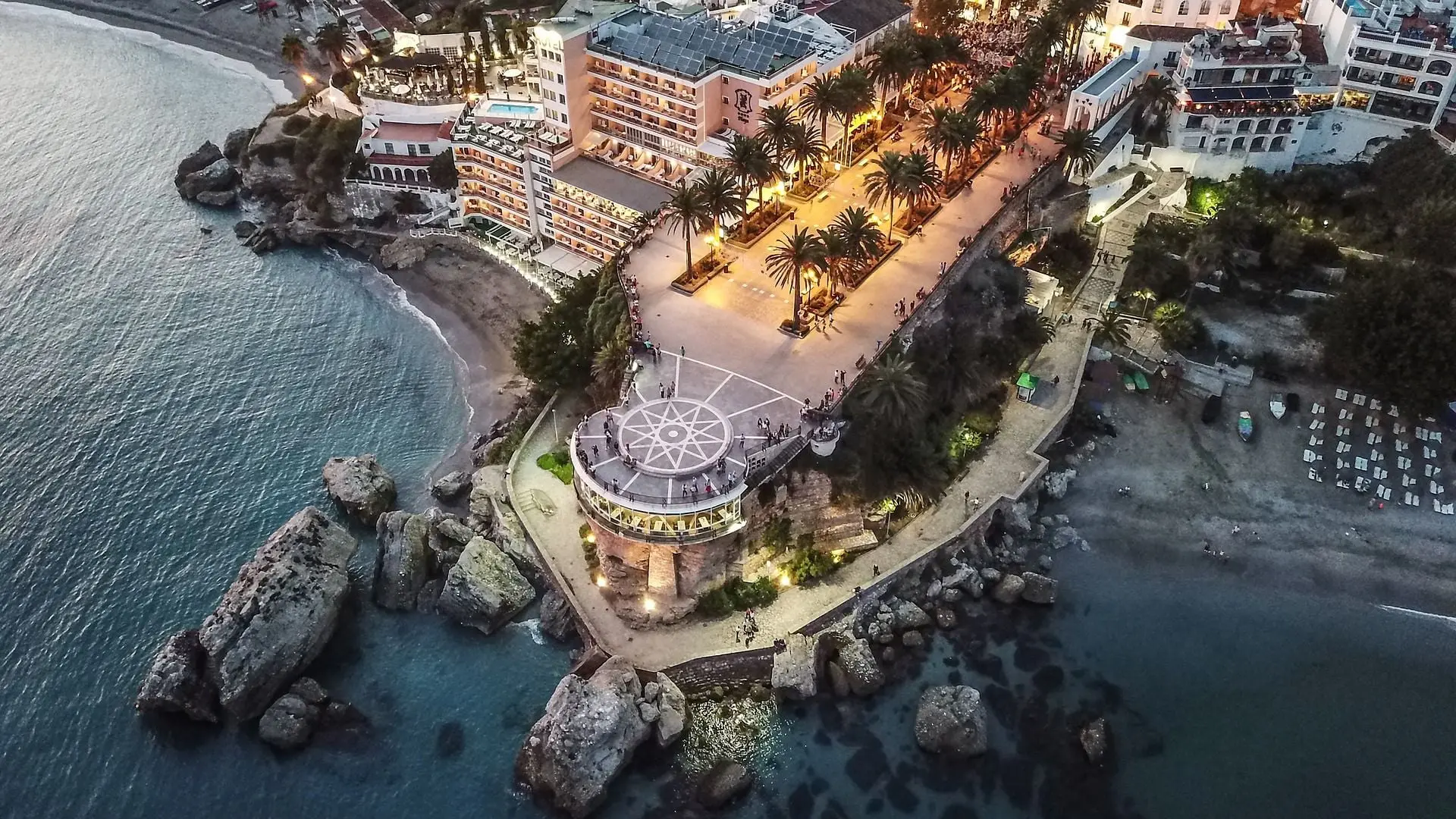 Balcón de Europa visto desde el aire al anochecer, con su paseo de palmeras y las rocas del mar