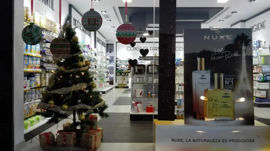 Interior de la farmacia decorado por Navidad con árbol, regalos y expositor de cosmética