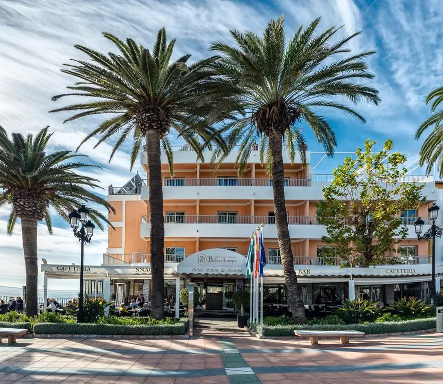 Fachada del Hotel Balcón de Europa entre palmeras, con su cafetería y terraza en el paseo