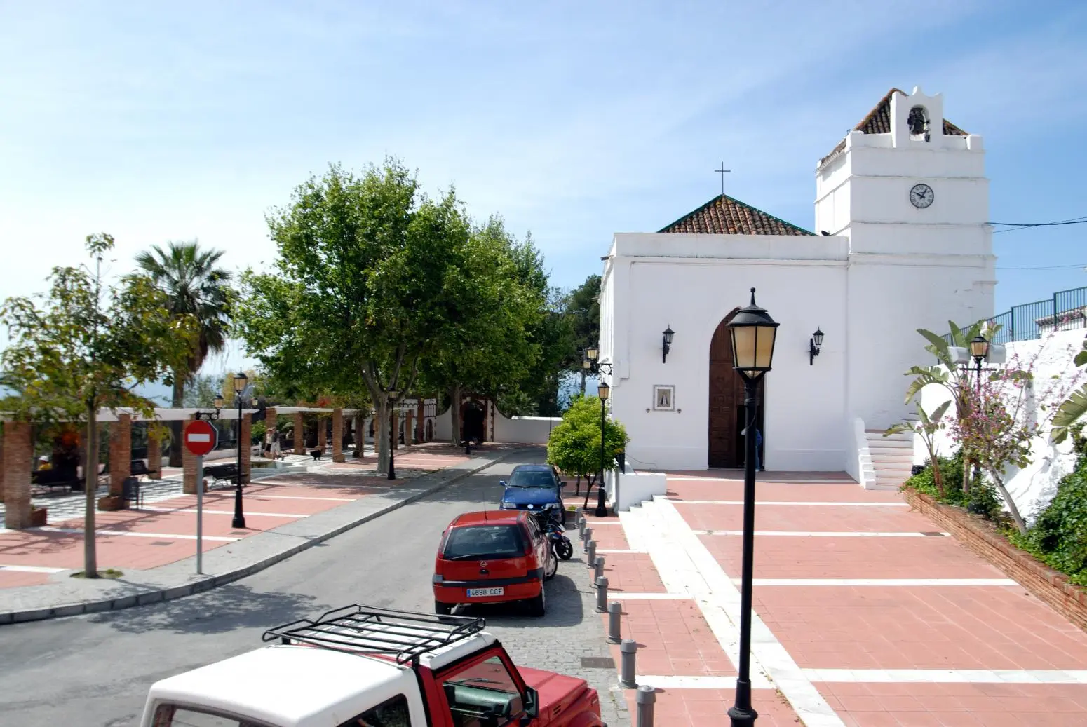 Plaza frente a la iglesia de Nuestra Señora de las Maravillas, con coches aparcados y árboles