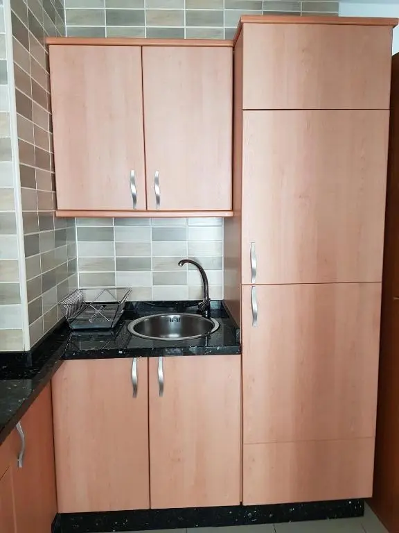 Fregadero de acero con escurreplatos y armarios de madera clara en la cocina