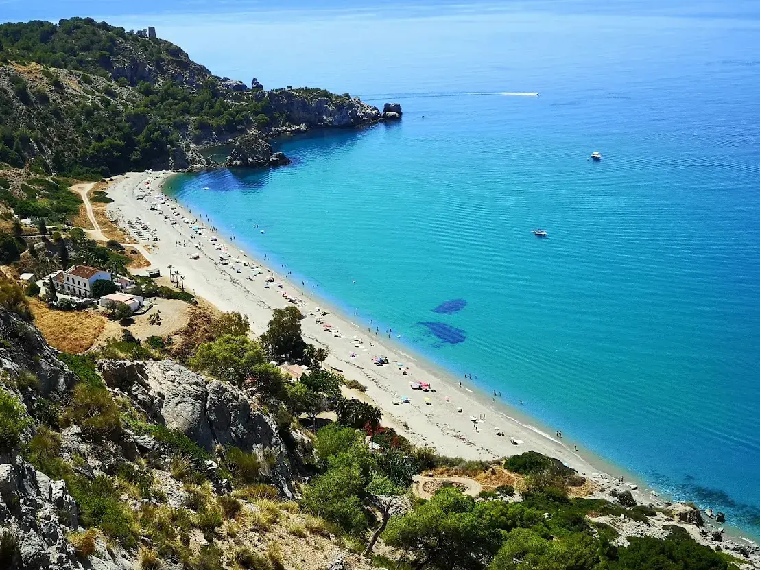 Vista aérea de la playa El Cañuelo, larga y con agua turquesa, entre los acantilados de Maro