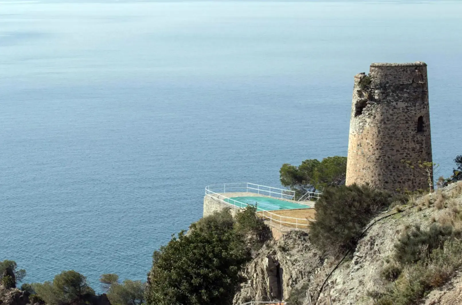 Torre vigía del Pino sobre el acantilado, junto a una piscina con vistas al mar