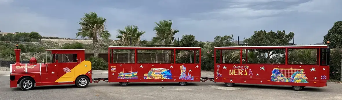 Locomotora y dos vagones rojos decorados con dibujos de la Cueva de Nerja, vistos de lado