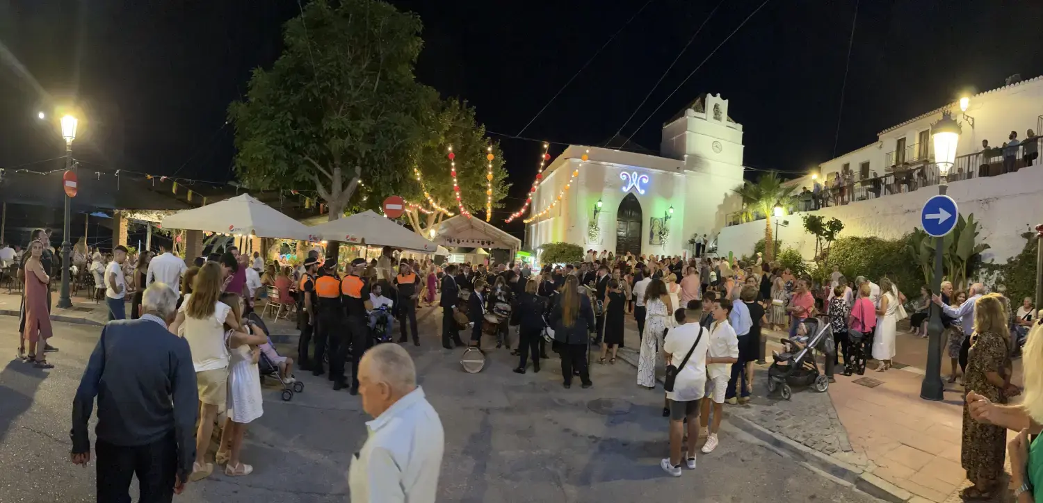 Gente reunida de noche ante la iglesia iluminada de Maro durante la feria