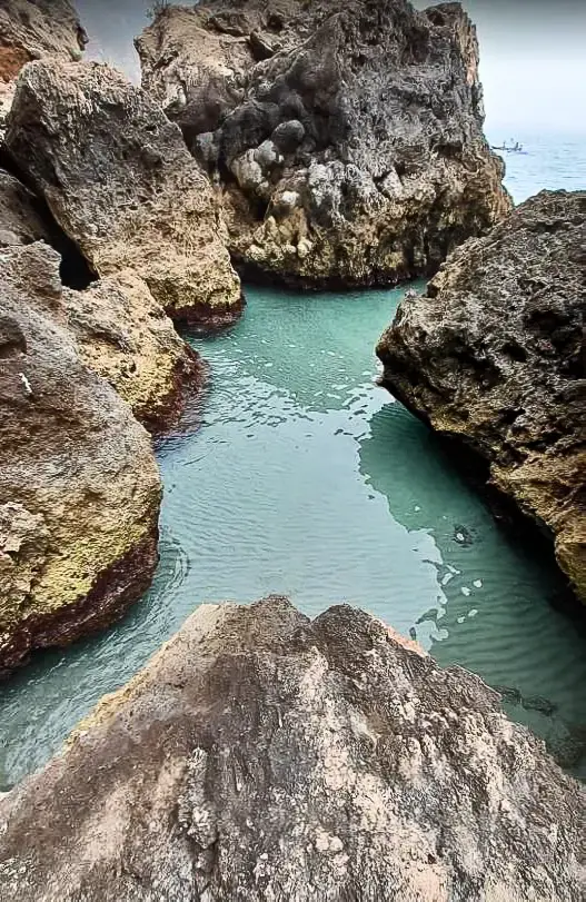Canal de agua verde azulada entre rocas en La Caleta de Maro