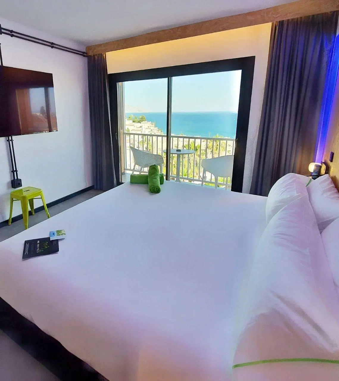 Habitación doble con cama grande y balcón con vistas al mar sobre los tejados