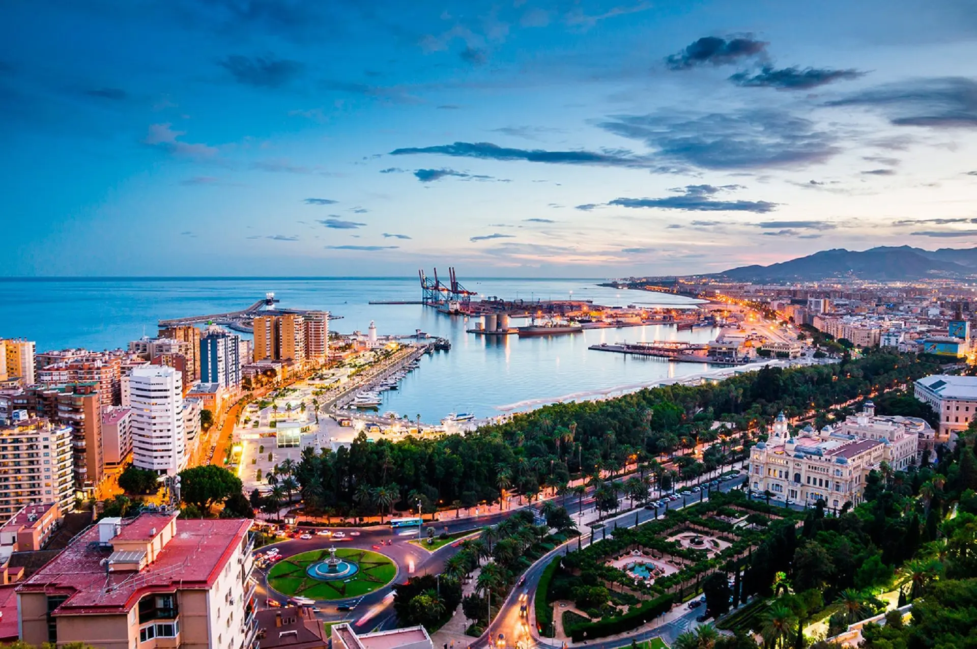Vista de Málaga al anochecer con el puerto, el Paseo del Parque y la ciudad iluminada