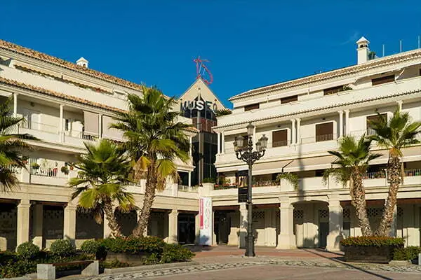 Fachada del Museo de Nerja en la Plaza de España, con soportales blancos y palmeras