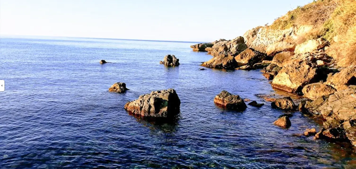 Rocas dispersas en el agua junto a la costa de La Caleta de Maro