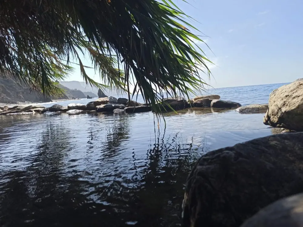 Poza de agua remansada entre piedras a la orilla de la playa del Molino de Papel