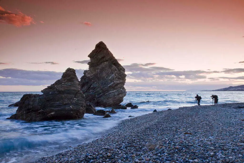 Fotógrafos al atardecer en la orilla de guijarros del Molino de Papel, junto a sus rocas puntiagudas