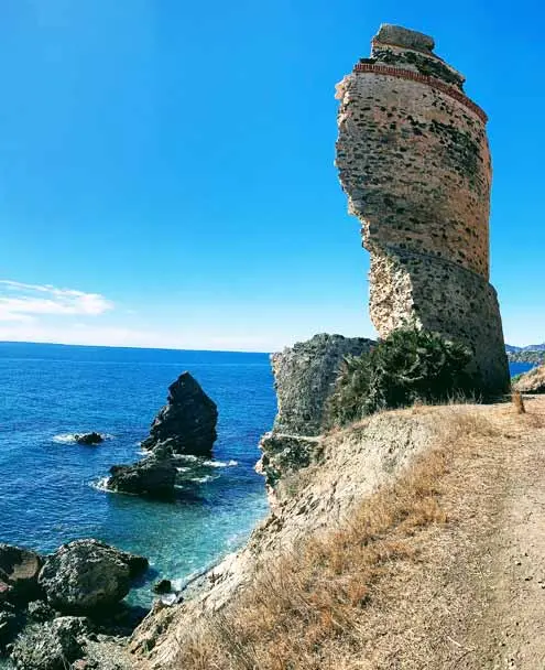 Torre vigía en ruinas sobre el acantilado de la playa del Molino de Papel, con rocas en el mar