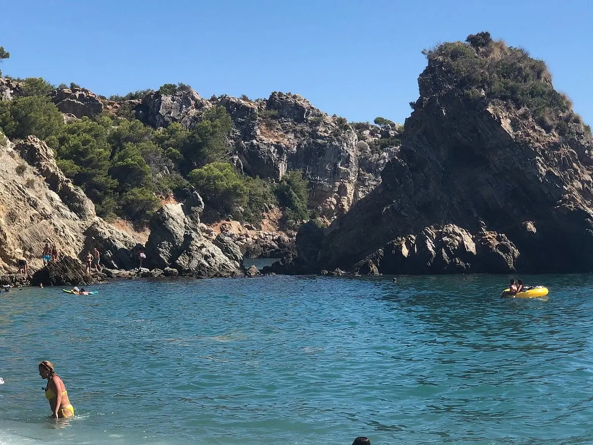 Bañistas y un flotador amarillo junto a las rocas de la playa El Cañuelo