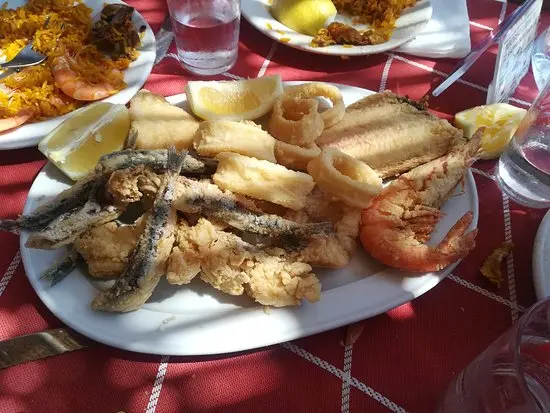 Fritura de pescado variado con calamares, boquerones y gambas sobre mantel de cuadros rojos