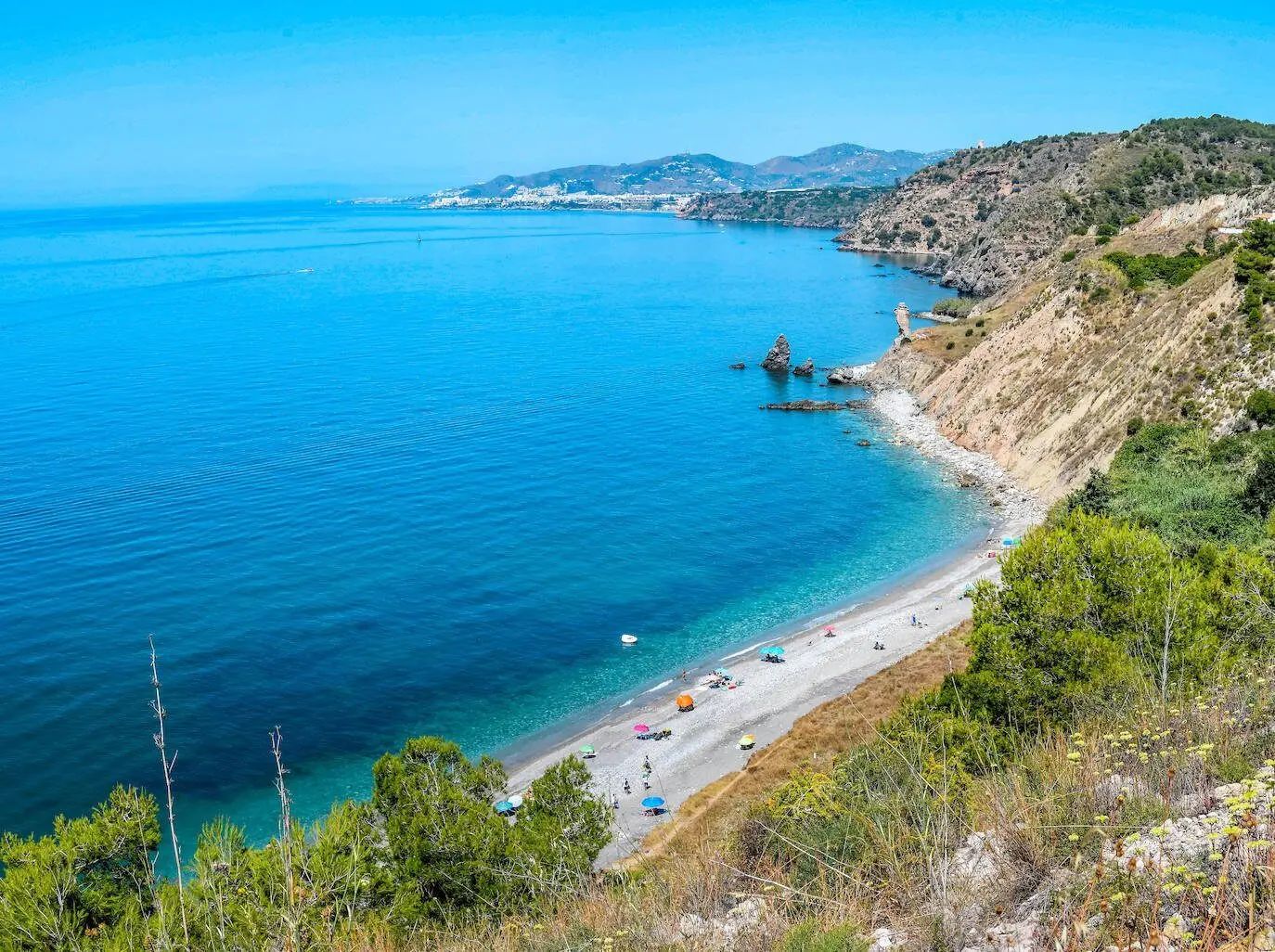 Panorámica de la playa de las Alberquillas con sombrillas y la costa de Nerja al fondo
