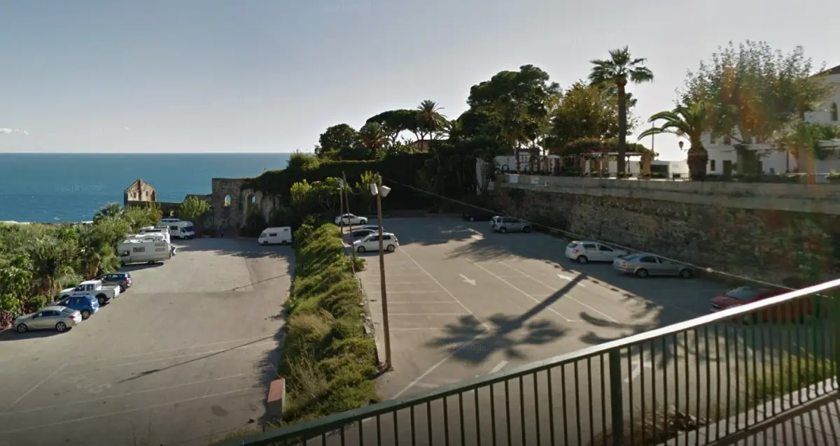Plazas del aparcamiento de Maro entre palmeras y setos, con vistas al Mediterráneo