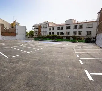 Plazas recién pintadas y vacías en el aparcamiento asfaltado, rodeado de bloques de viviendas