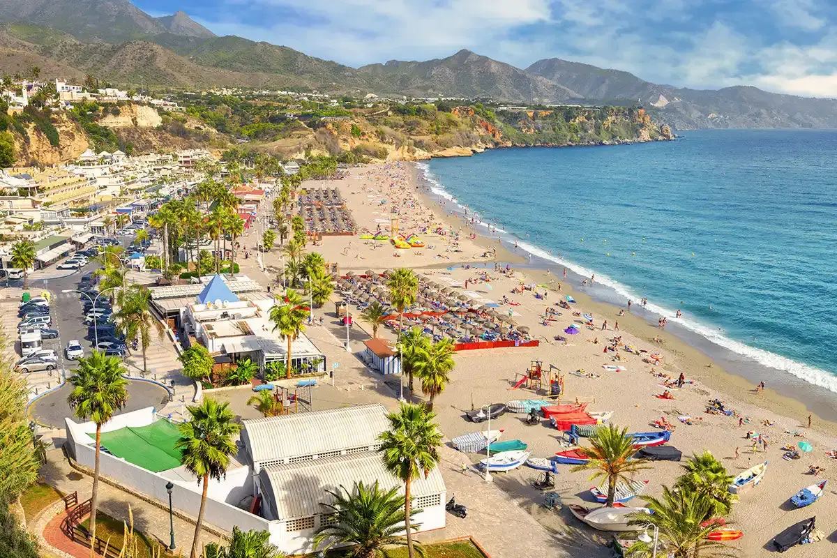 Panorámica de Burriana con hamacas, barcas de pesca y el paseo con palmeras, en Nerja