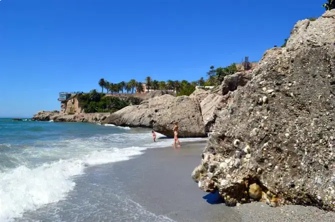Bañistas junto a la roca de conglomerado en la orilla de la playa El Chorrillo