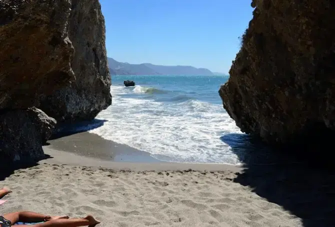 El mar entre dos paredes de roca en la playa El Chorrillo, con olas en la arena