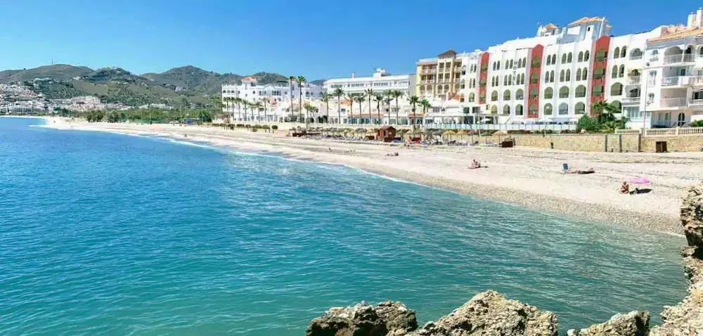 Agua turquesa y orilla de la playa El Chucho frente a los hoteles del paseo
