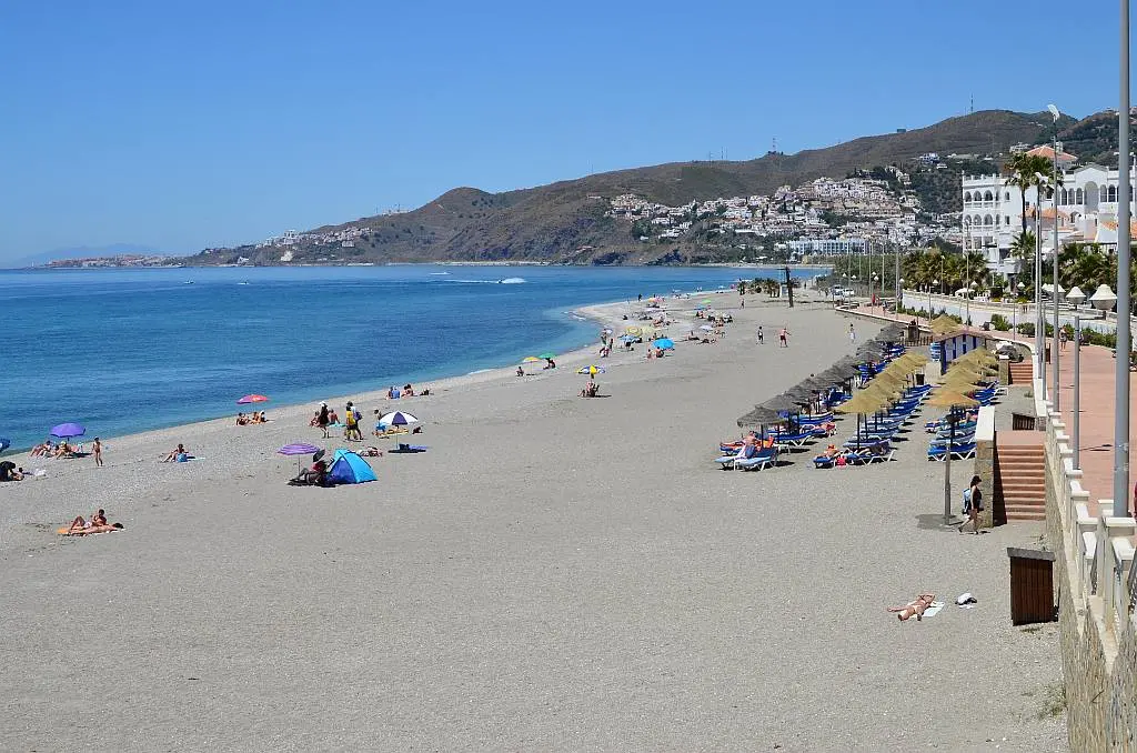 Hamacas con sombrillas de paja junto al paseo en la playa El Chucho