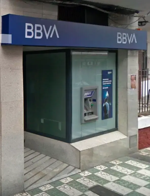 Cajero automático de BBVA en una esquina, bajo el rótulo azul y junto a la entrada