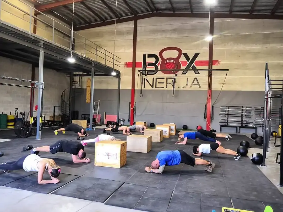 Clase en grupo haciendo planchas entre cajones de salto en la nave de BOX Nerja