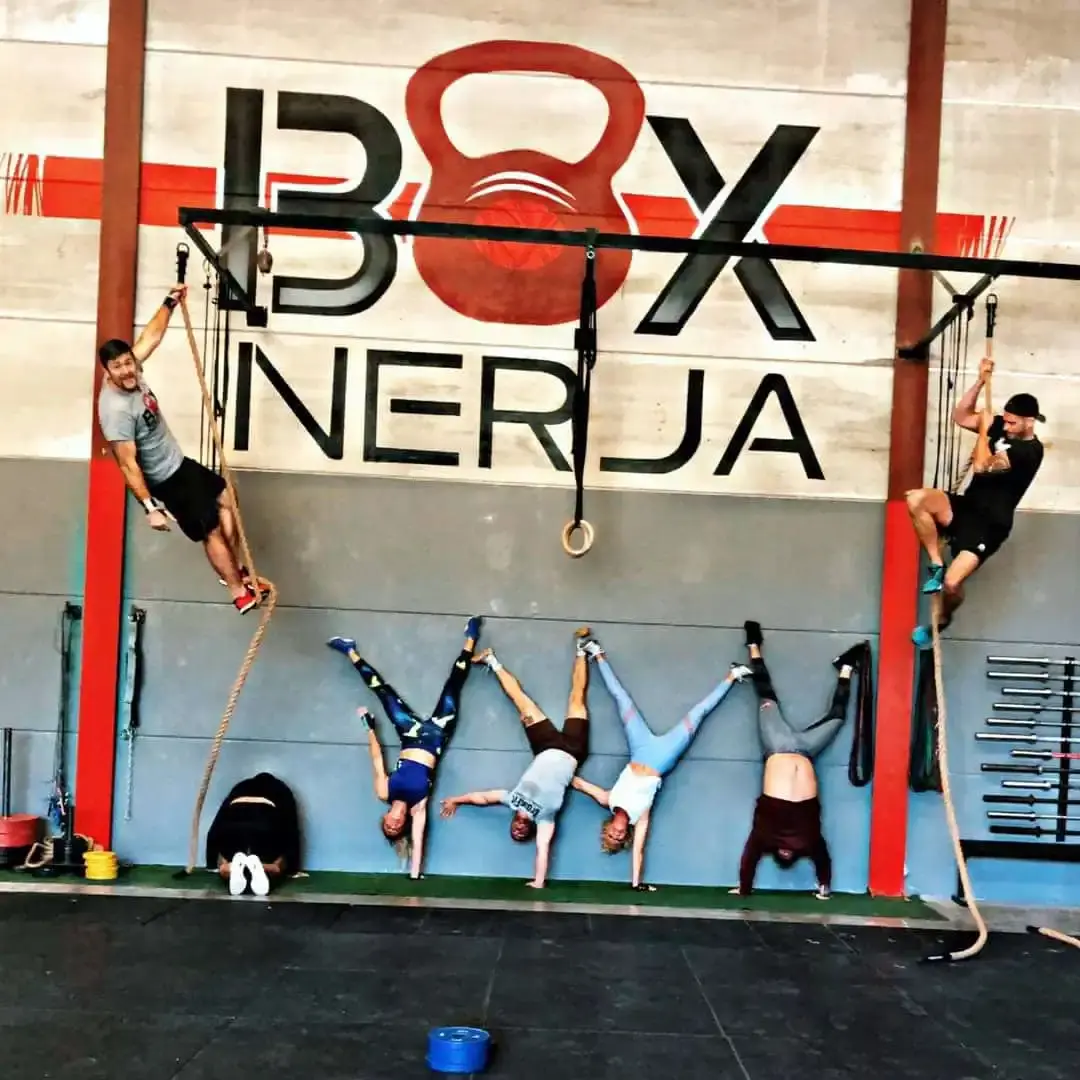 Deportistas haciendo el pino y trepando cuerdas bajo el logotipo de BOX Nerja