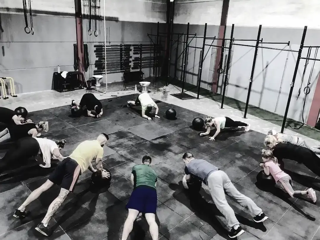 Entrenamiento en grupo con balones medicinales sobre el suelo de caucho, junto a los racks de dominadas