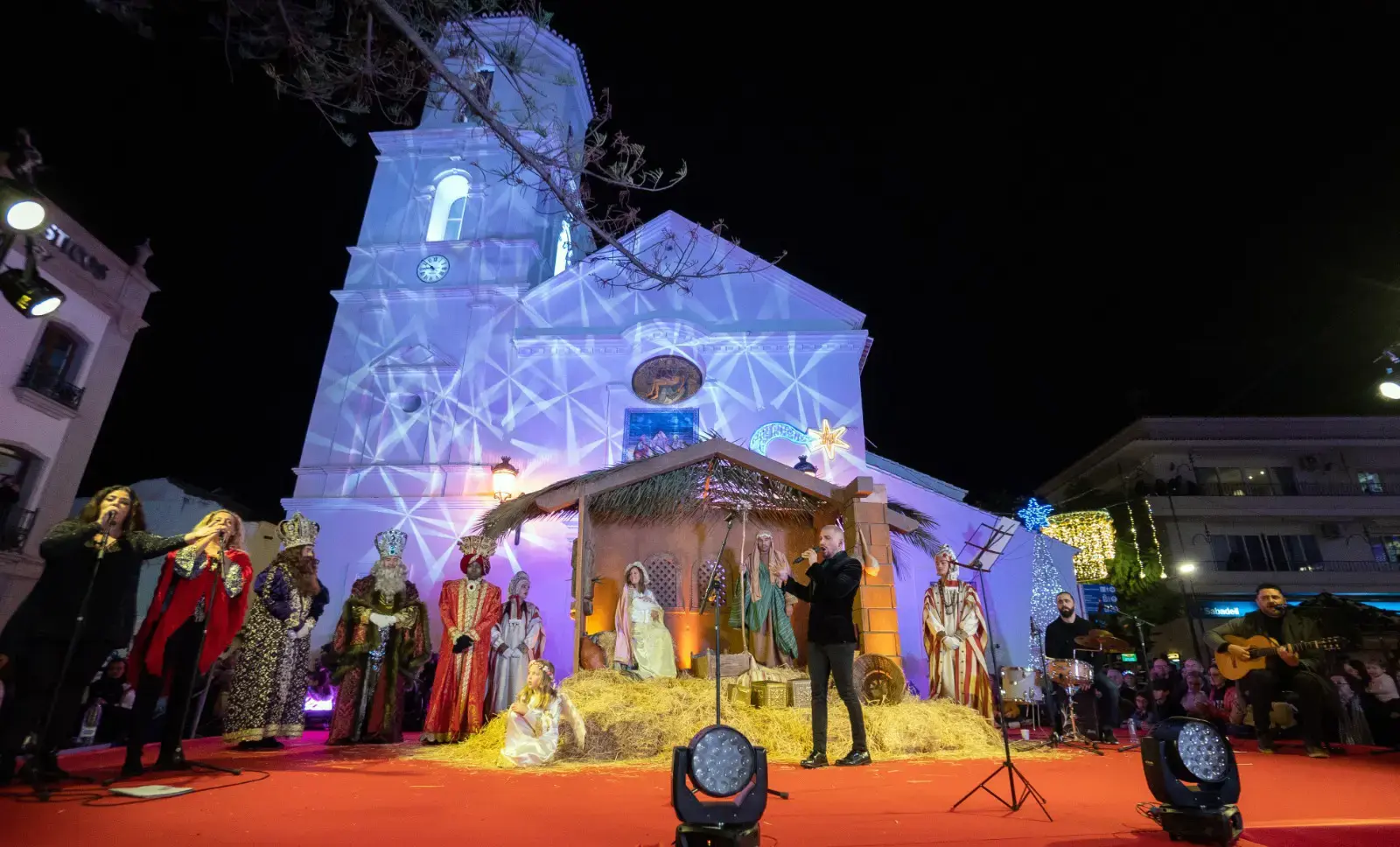 Belén viviente y los Reyes Magos en un escenario ante la iglesia de El Salvador iluminada de noche