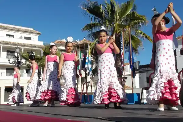 Niñas con trajes de flamenca de lunares bailando en el escenario del Día del Residente en Nerja