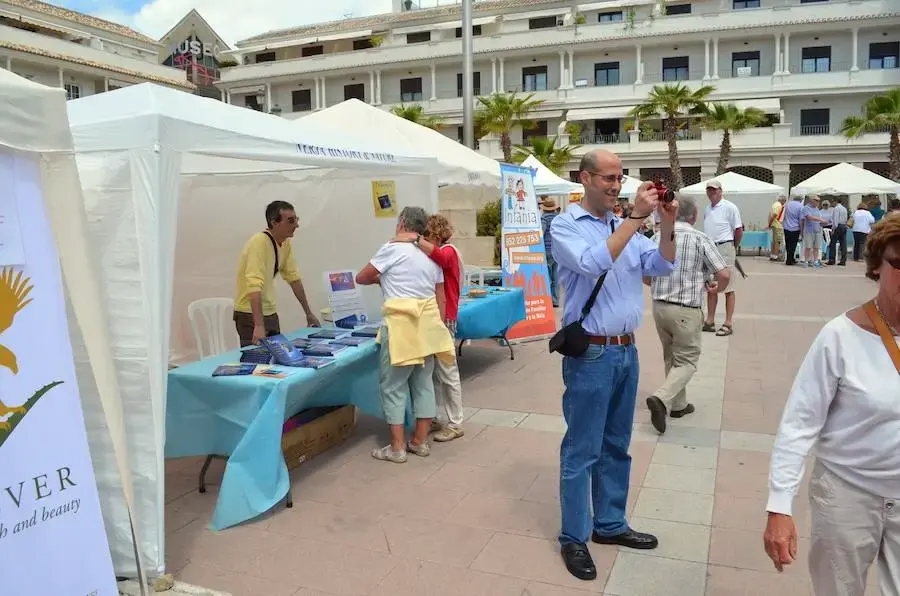 Carpas blancas con puestos informativos de asociaciones en la plaza y visitantes paseando