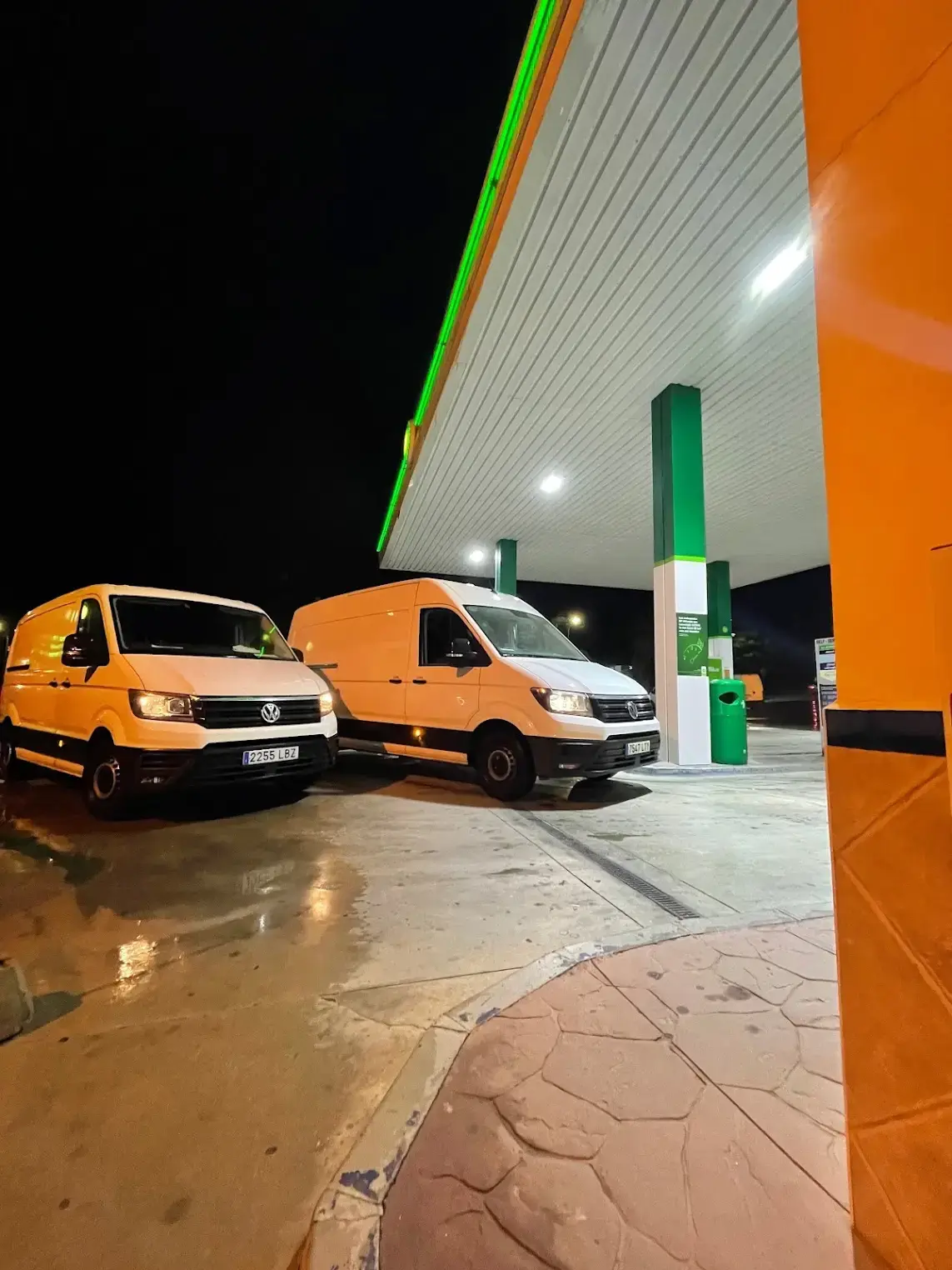 Furgonetas paradas bajo la marquesina iluminada de la gasolinera de noche