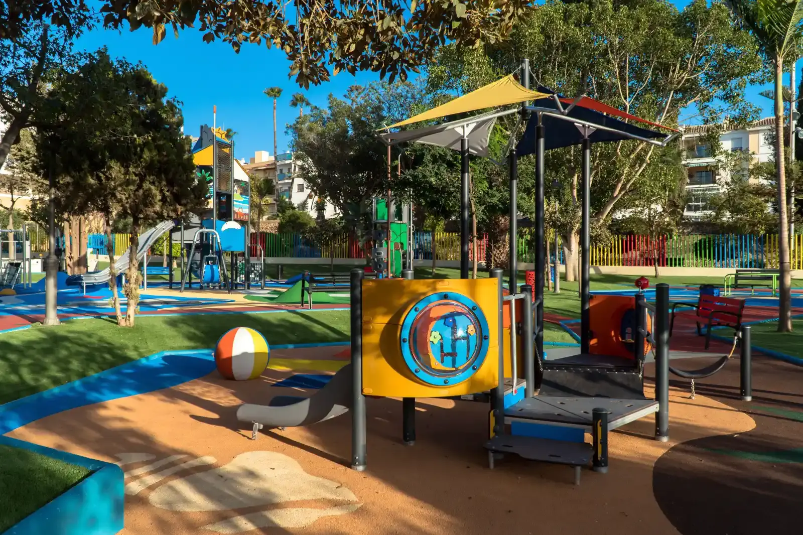 Zona de juegos para los más pequeños con tejadillos de colores y una gran pelota de playa decorativa