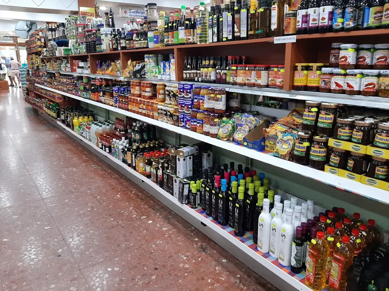 Estanterías con aceites de oliva, vinos, conservas y salsas en un pasillo del Supermercado Iranzo