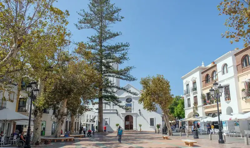 Plaza frente a la Iglesia de El Salvador en Nerja, con árboles, farolas y terrazas