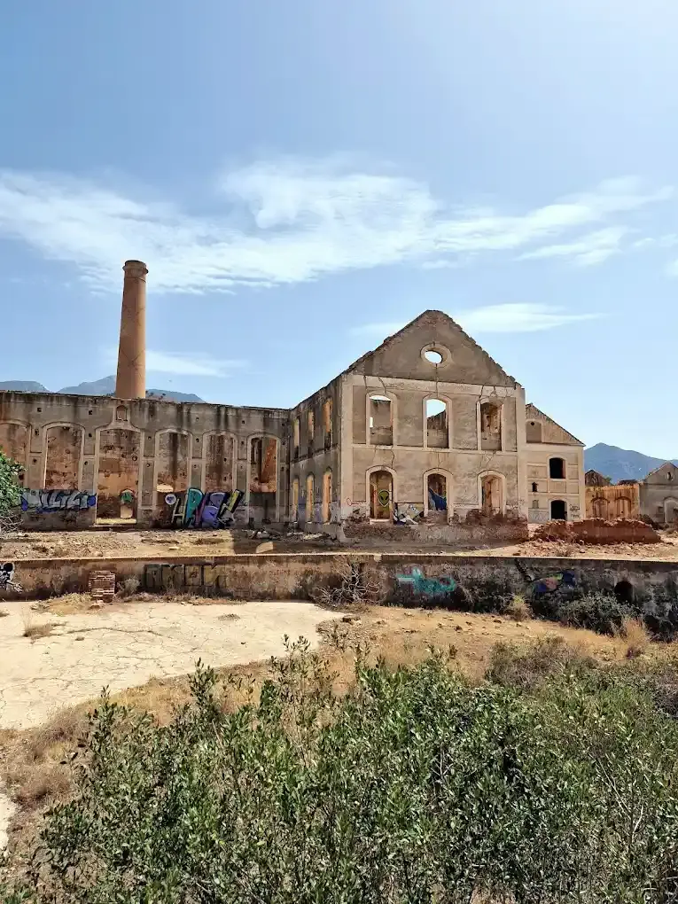 Nave principal de la fábrica de azúcar y la chimenea, con matorral en primer plano