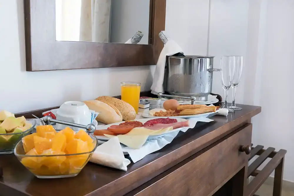 Desayuno servido en la habitación con fruta, embutidos, pan, zumo y cava en cubitera