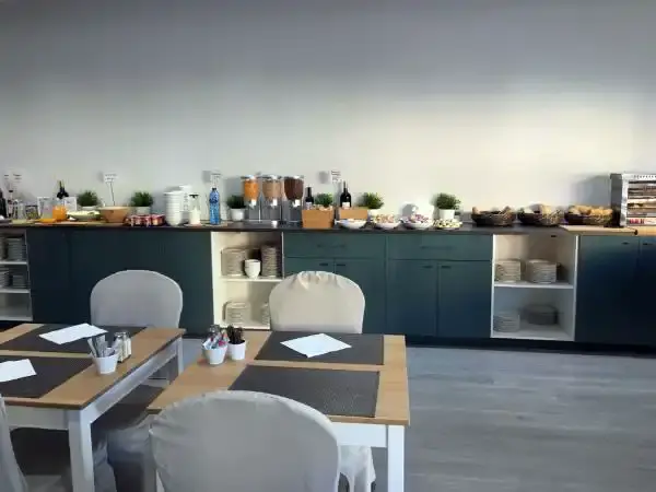 Comedor del desayuno con mesas puestas y bufé a lo largo de la pared