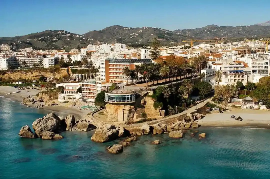 El Balcón de Europa visto desde las rocas, con el pueblo de Nerja al fondo