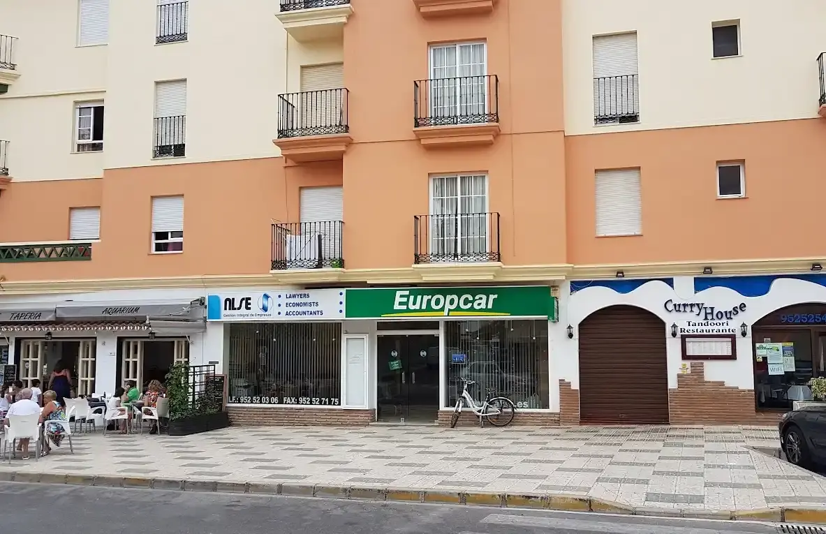 Oficina de alquiler de coches Europcar en los bajos de un edificio junto a otros comercios