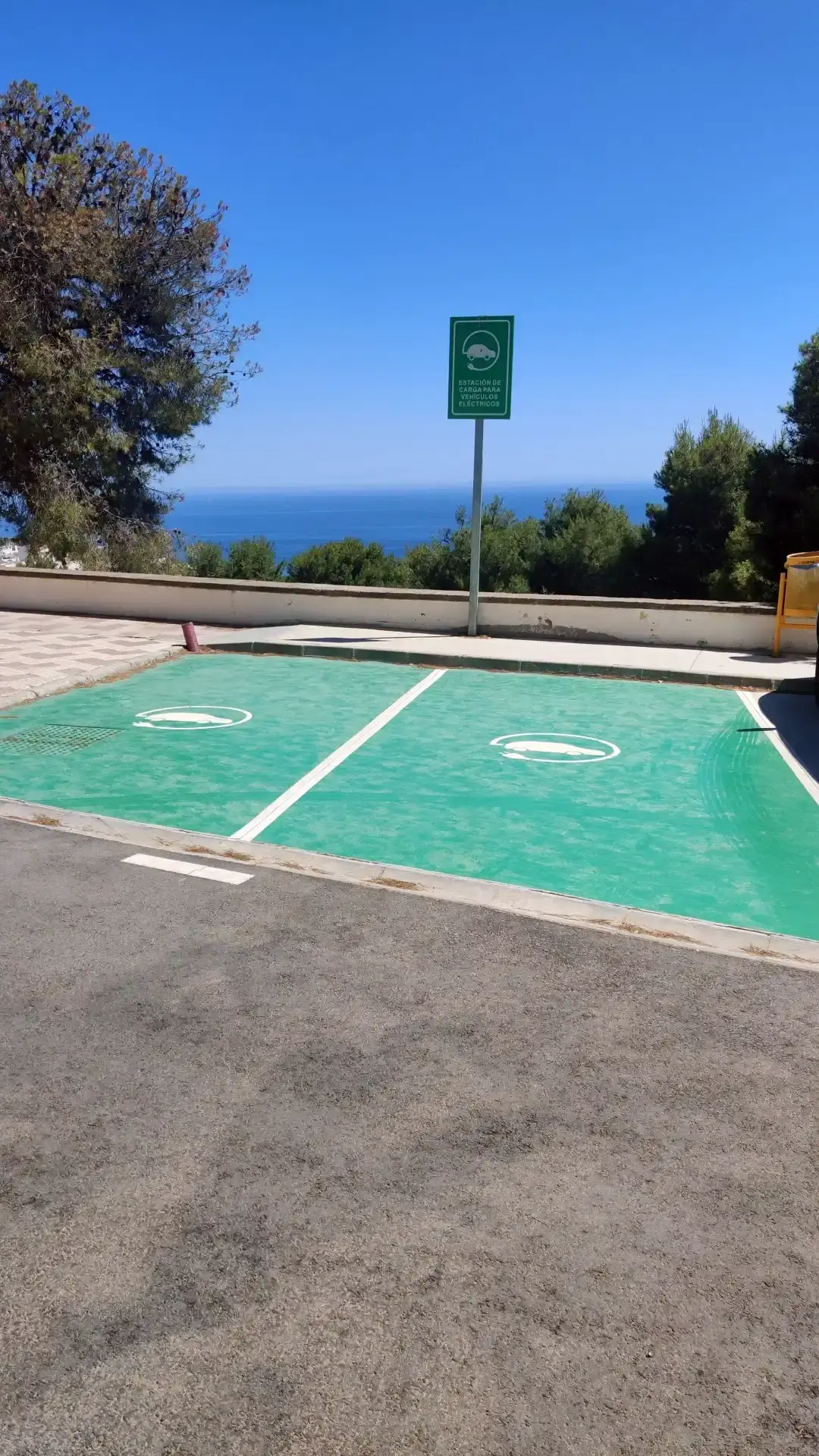 Plazas pintadas de verde para recarga de coches eléctricos con el mar al fondo