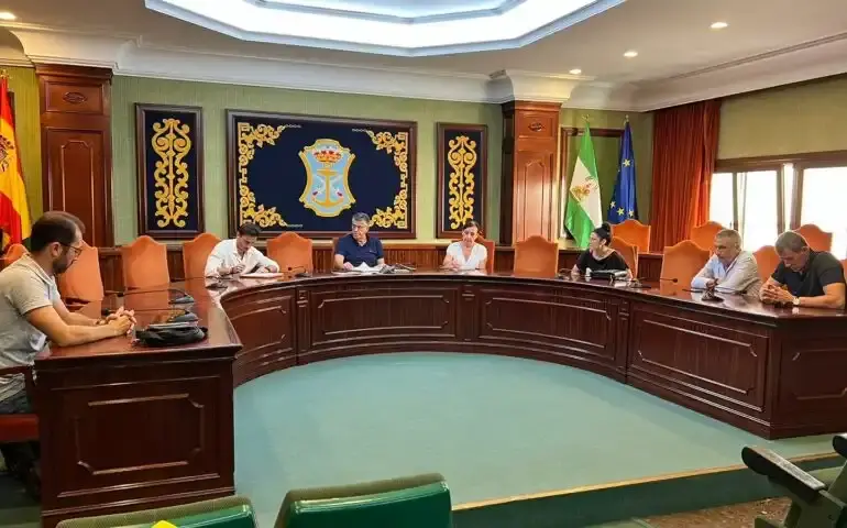 Salón de plenos con el escudo de Nerja y concejales reunidos en la mesa semicircular