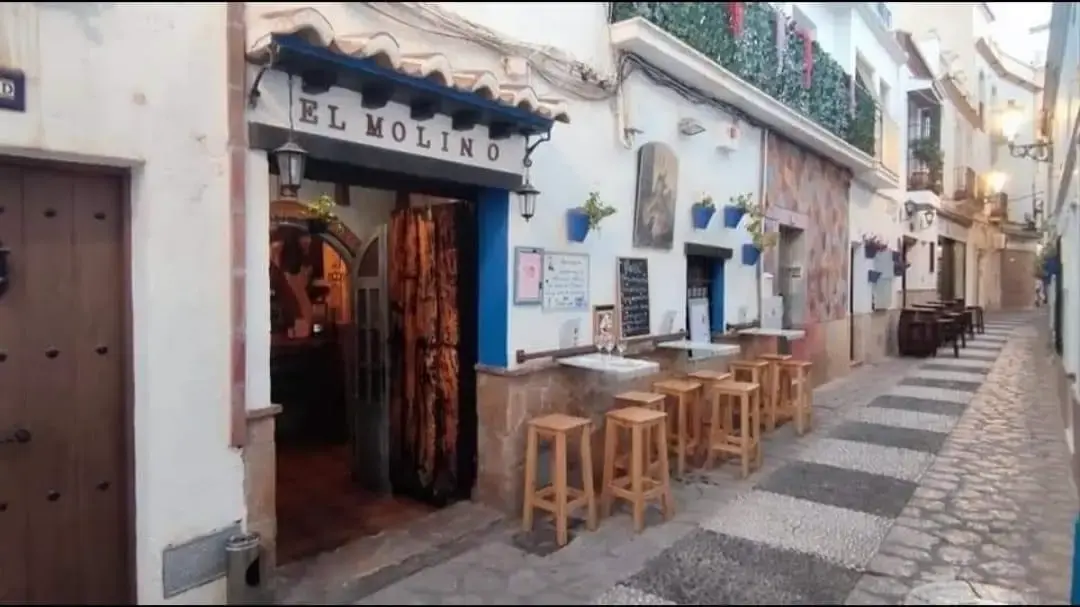 Fachada del bar El Molino en una calle estrecha del casco antiguo, con taburetes de madera