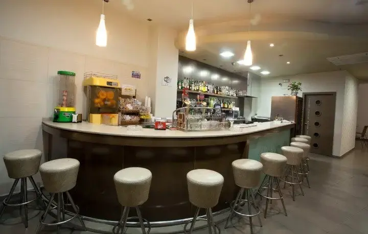 Barra de la cafetería con taburetes, exprimidor de naranjas y estantería de bebidas